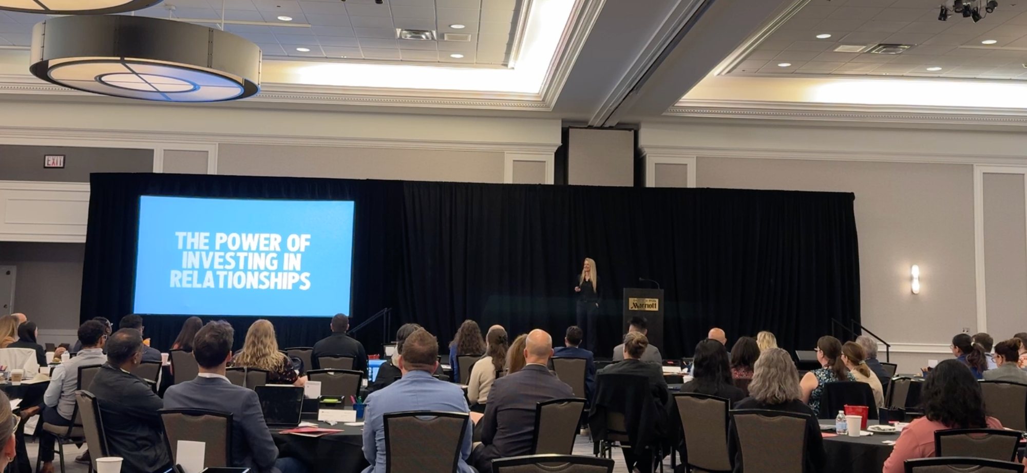 Bridget speaking to a ballroom audience with