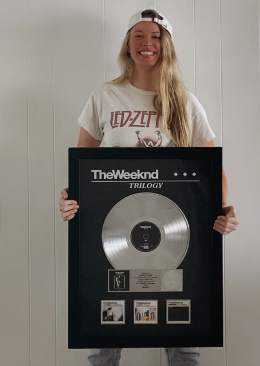 Bridget Hilton holding The Weeknd Trilogy platinum plaque